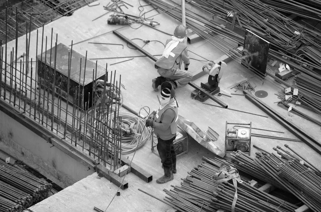 Workers on a construction site among steel reinforcement bars and pipes